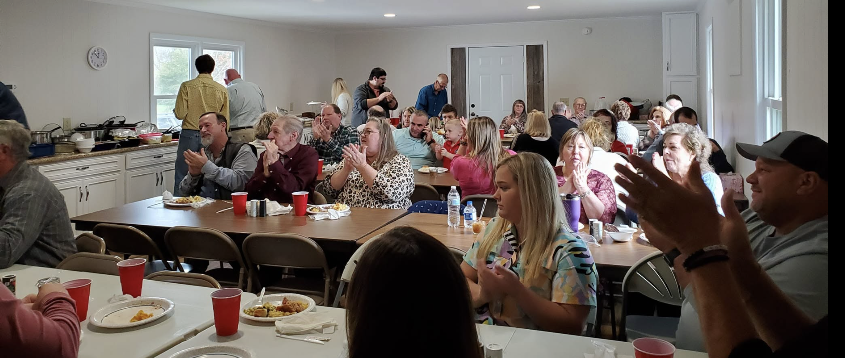 Church family sharing a fellowship meal together around long tables